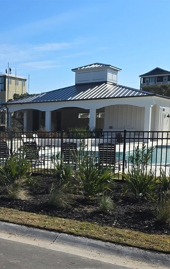 Landscape installation around a community pool featuring fresh mulch, ornamental grasses, flowering plants, and professionally maintained landscape beds.